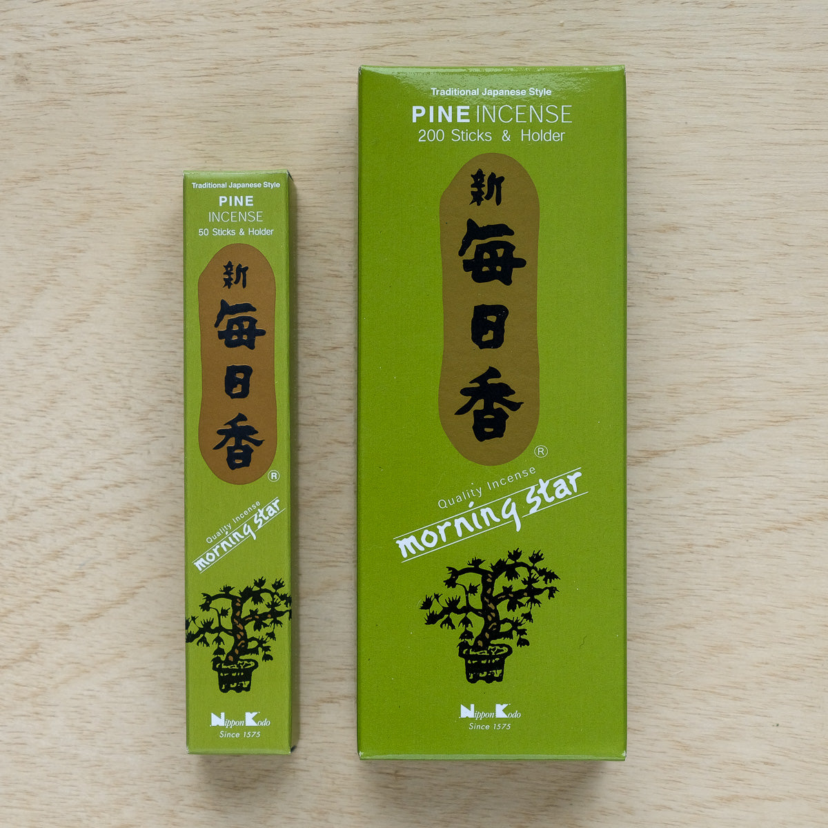 Two green boxes of Morning Star Pine Incense are displayed on a wooden surface. The smaller box contains 50 sticks, while the larger one holds 200, each with traditional Japanese-style branding and illustrations. Ideal for enhancing your meditation experience.