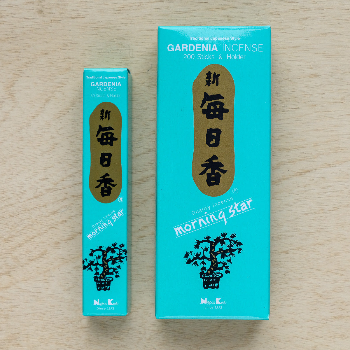 Two teal boxes of Morning Star Gardenia Incense, one labeled 200 sticks & holder and the other 50, rest on a wooden surface. They feature white and gold text with a floral design, capturing the essence of traditional Japanese incense and pure floral essences.