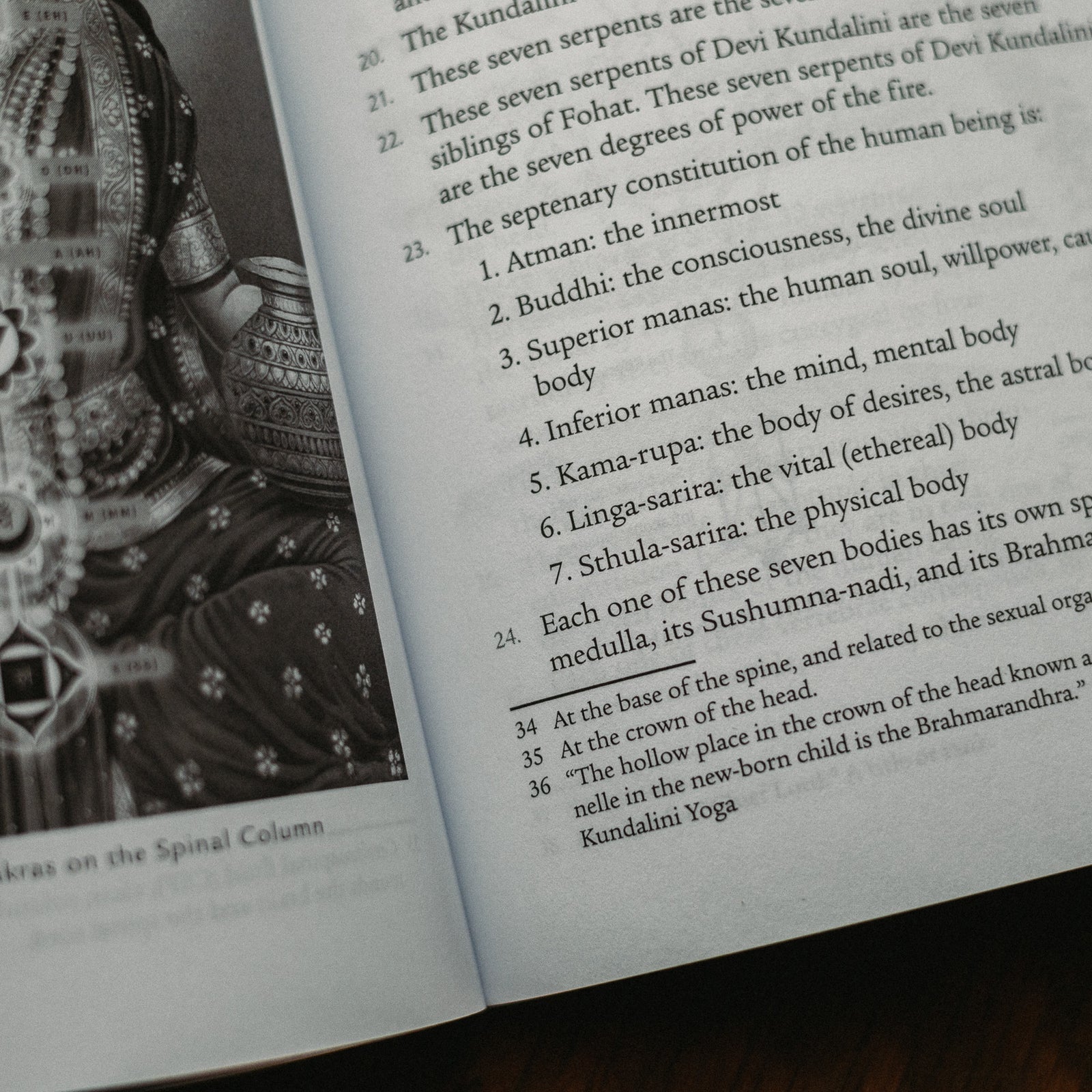 An open book shows a black-and-white image and text; the left page illustrates a person in ornate attire, radiating spirituality, while the right page details consciousness and human body aspects, hinting at awakening Kundalini energy. Product: Kundalini: The Sacred Fire of All Religions.