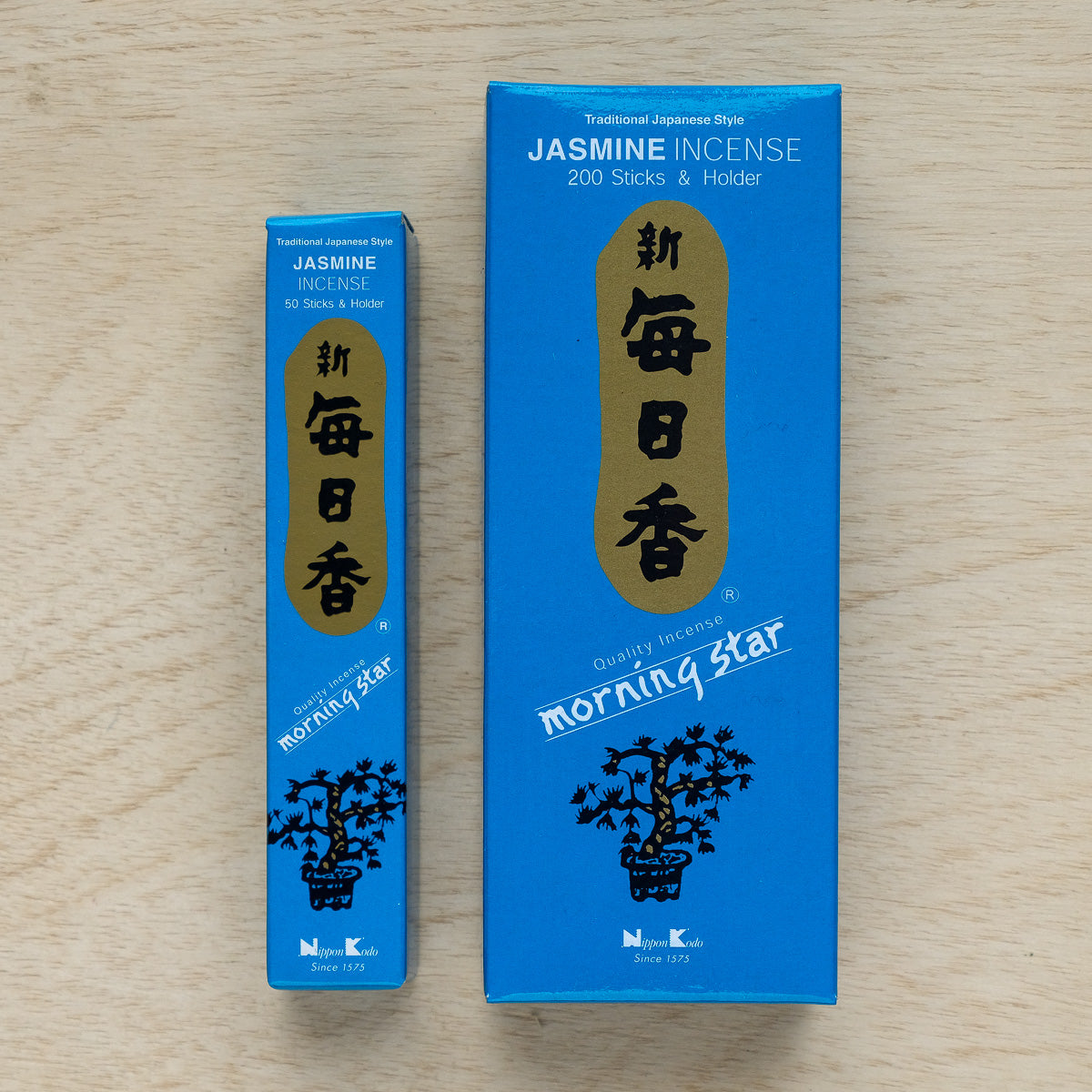 Two blue boxes of Morning Star Jasmine Incense sit on a wooden surface. One small box holds 50 sticks, and the larger one contains 200 sticks with a holder. The traditional Japanese branding features gold and white accents, ideal for enhancing your meditation routine.
