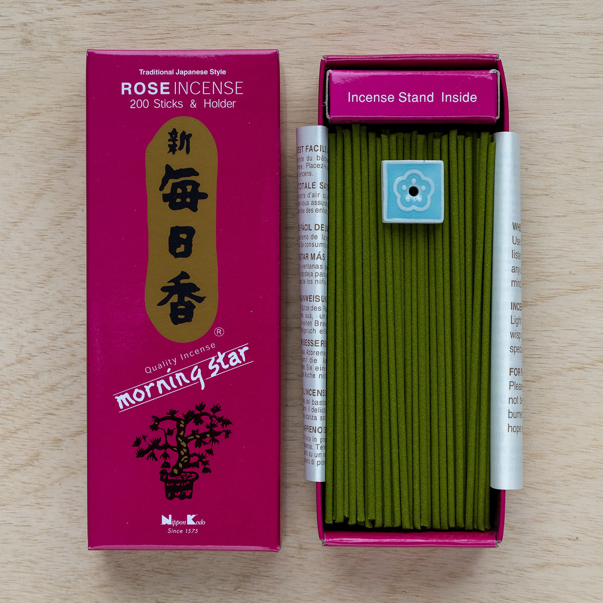 A box of Morning Star Rose Incense features green sticks and a small blue holder. The pink packaging with gold accents showcases delicate floral designs, capturing the traditional Japanese incenses pure floral essences.