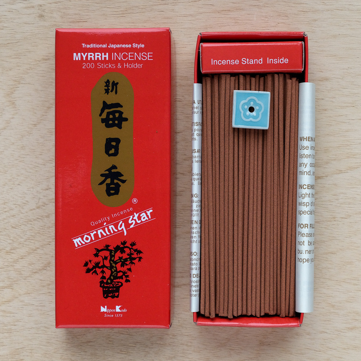 The Morning Star Myrrh Incense box features a floral logo and holds 200 brown sticks alongside a small blue holder. The red box offers the classic Japanese myrrh scent.