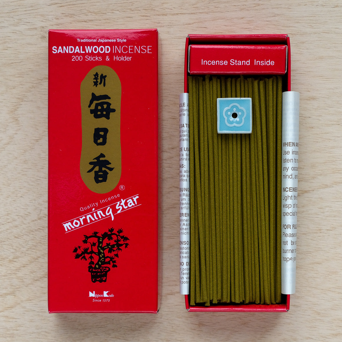 An open red box of Morning Star Sandalwood Incense reveals 200 sticks and a decorative holder with a blue flower design. The packaging elegantly displays the brand name and traditional Japanese writing.