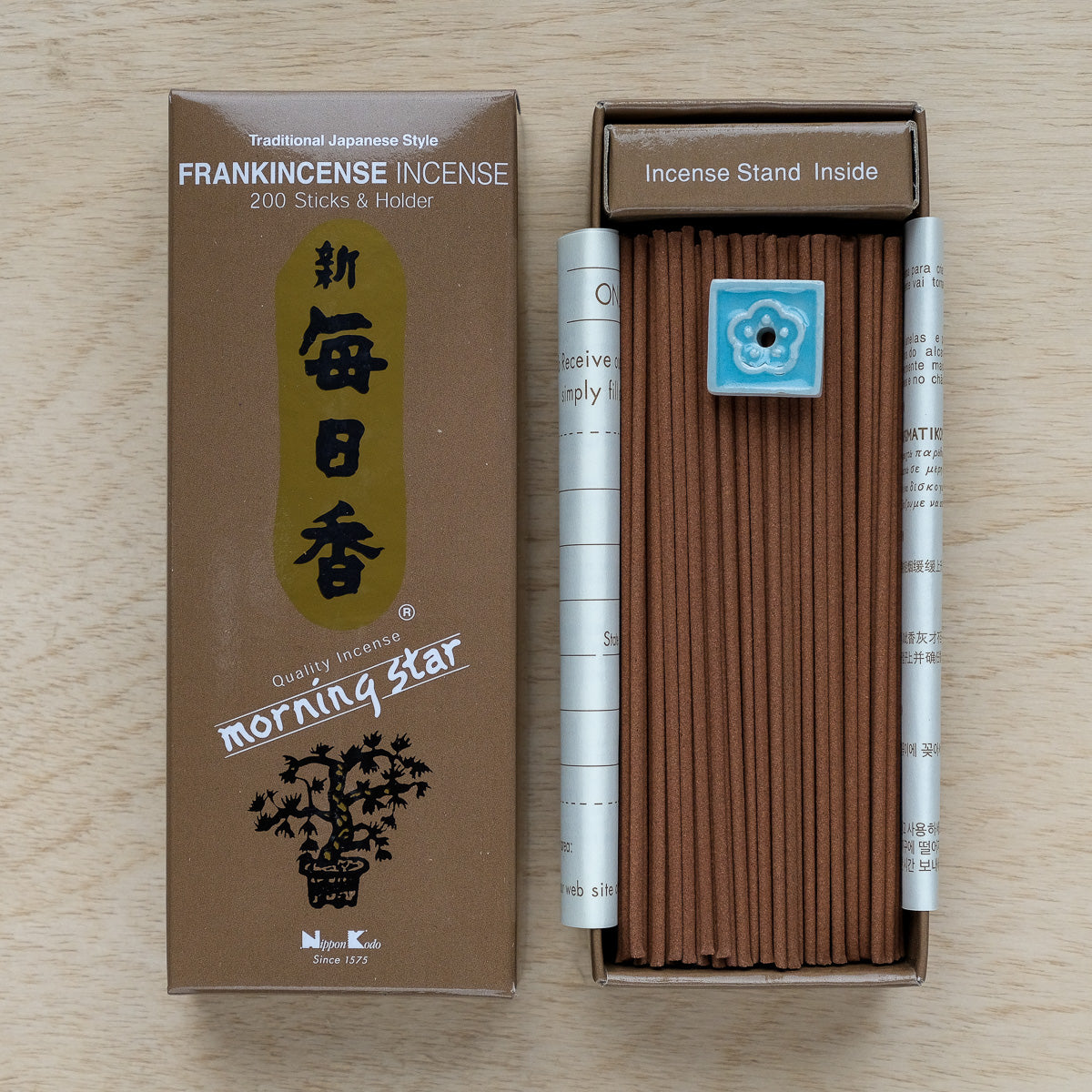 An opened box of Morning Star Frankincense Incense contains around 200 brown sticks, plus a small blue holder. The packaging features traditional Japanese design elements, ideal for fans of authentic Japanese incense experiences.
