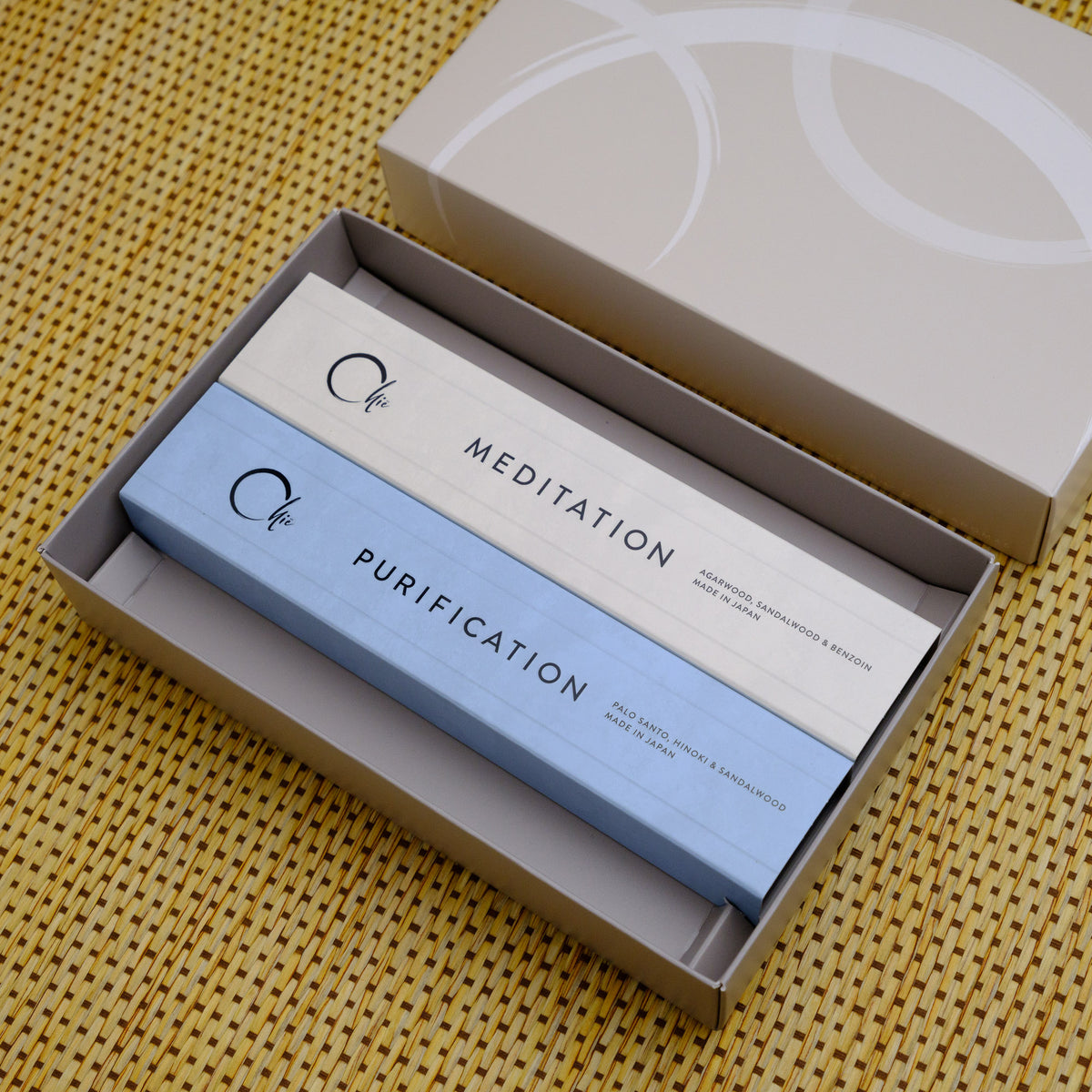 Two incense sticks labeled &#39;Meditation&#39; and &#39;Purification&#39; in an open box on a textured yellow surface.