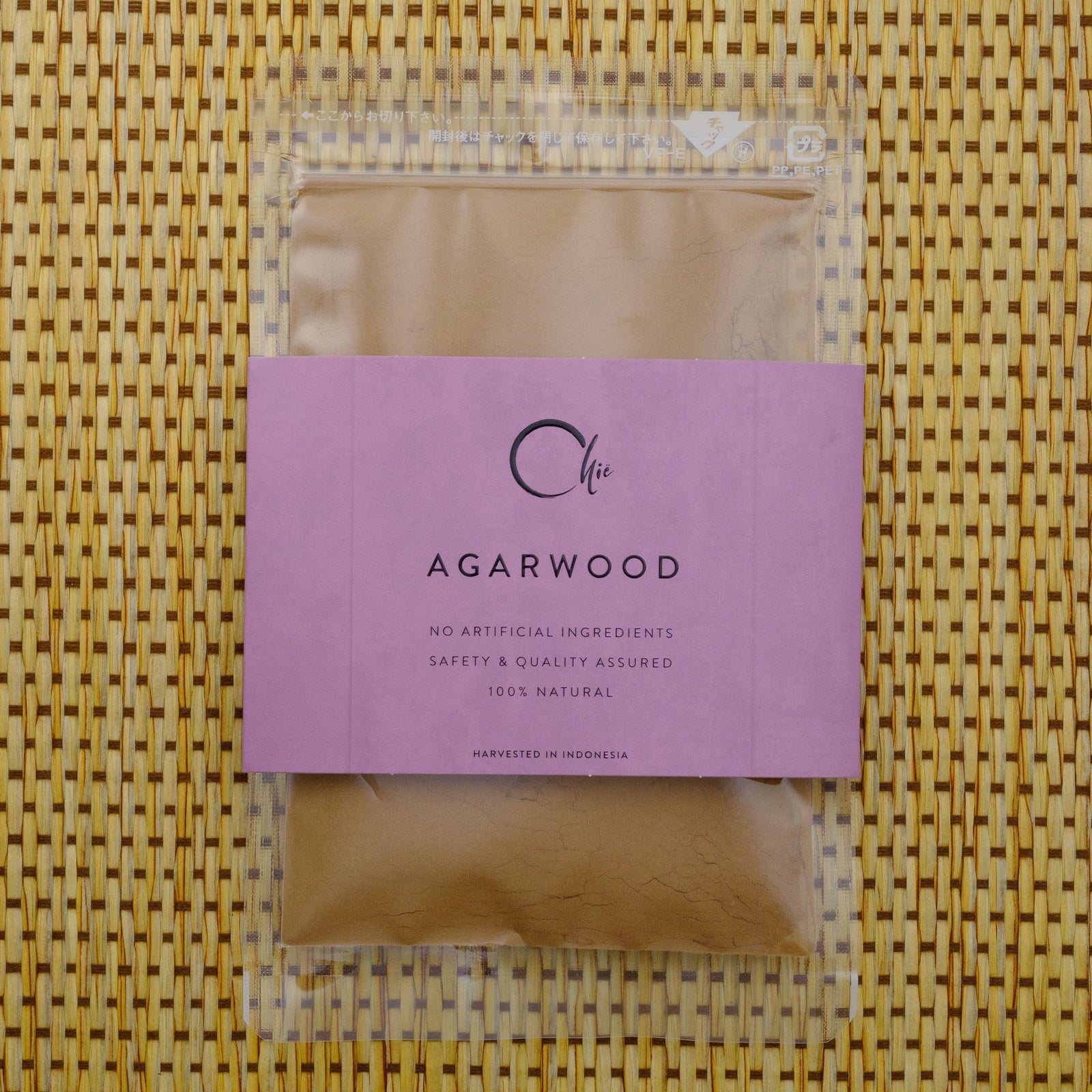 Package of agarwood with a pink label on a woven mat background