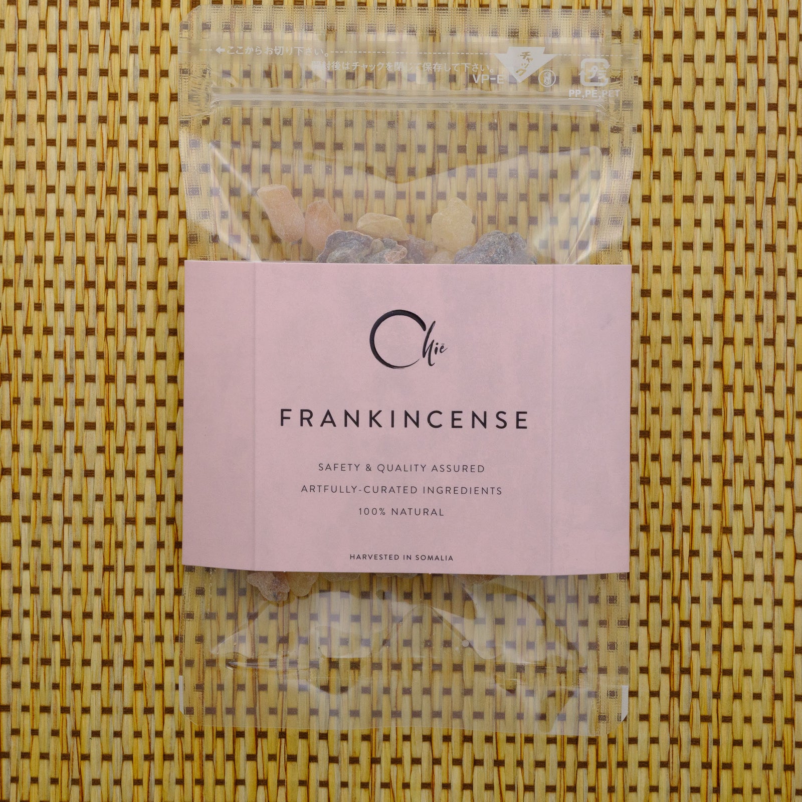 Packaged frankincense with a pink label on a woven surface