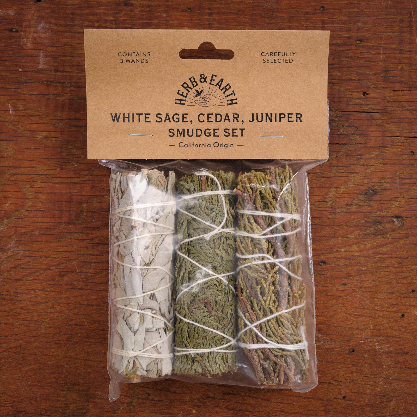 Herb & Earth White Sage, Cedar, Juniper Smudge Set packaging on a wooden surface