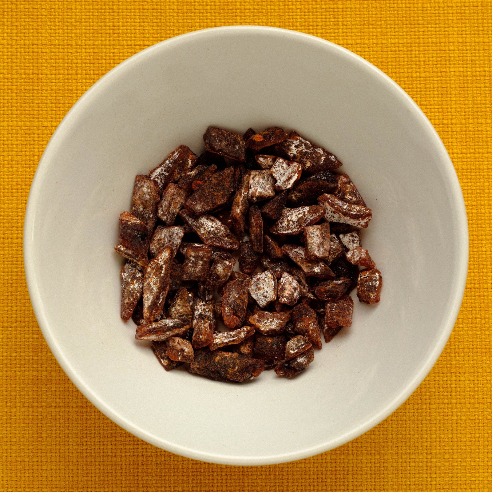 White bowl filled with sandalwood resin incense on a yellow background