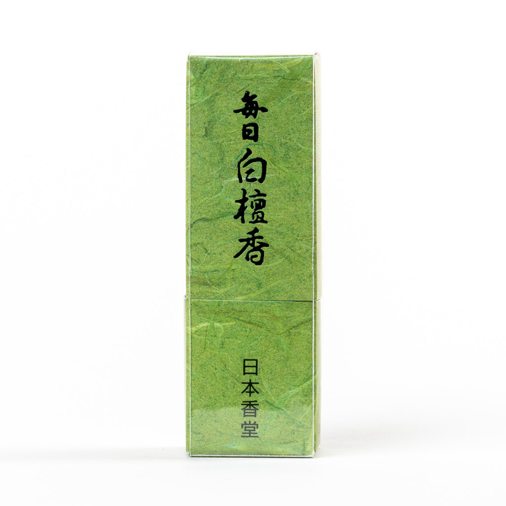 A textured green box labeled Mainichi Byakudan Premium Sandalwood Japanese Incense with black vertical script at the top and white at the bottom evokes a serene sandalwood aroma, reminiscent of calming meditation spaces.