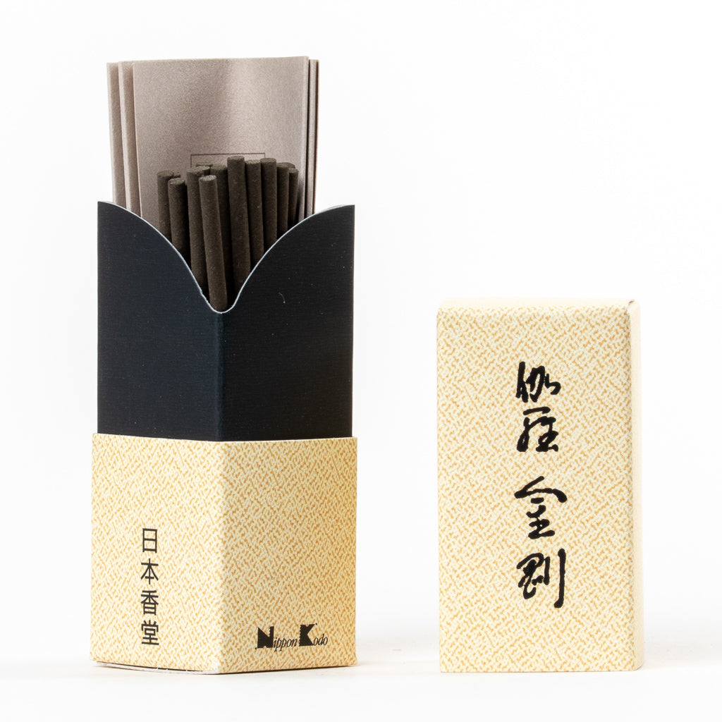 The Kyara Kongo Aloeswood Japanese Incense box, with a black and gold patterned base, reveals incense sticks inside. Its lid, adorned with Japanese characters, adds cultural charm.