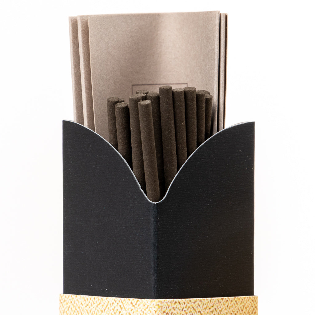 Inside the black open box, youll find several black incense sticks and beige paper packets, accented by a woven textured band. Crafted in traditional Japanese style, the Kyara Kongo Aloeswood Japanese Incense offers an exquisite fragrance against a plain white backdrop.