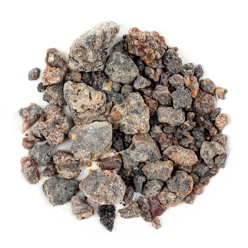 A collection of irregularly shaped Frankincense Resin Incense: First Grade Black (Boswellia neglecta from Ethiopia) rocks in grey, brown, and black hues lies on a white background, echoing the rugged terrain where Boswellia trees grow.
