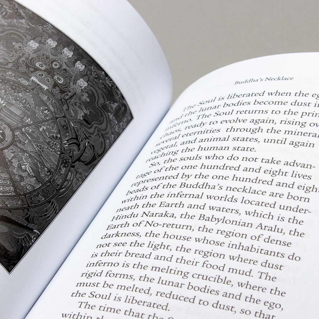 A close-up of a book open to Light from Darkness (2012 Edition) features an intricate grayscale illustration titled Buddhas Necklace. The text delves into spiritual awakening and consciousness. Resting on a flat surface, its slightly curved pages invite quiet contemplation.