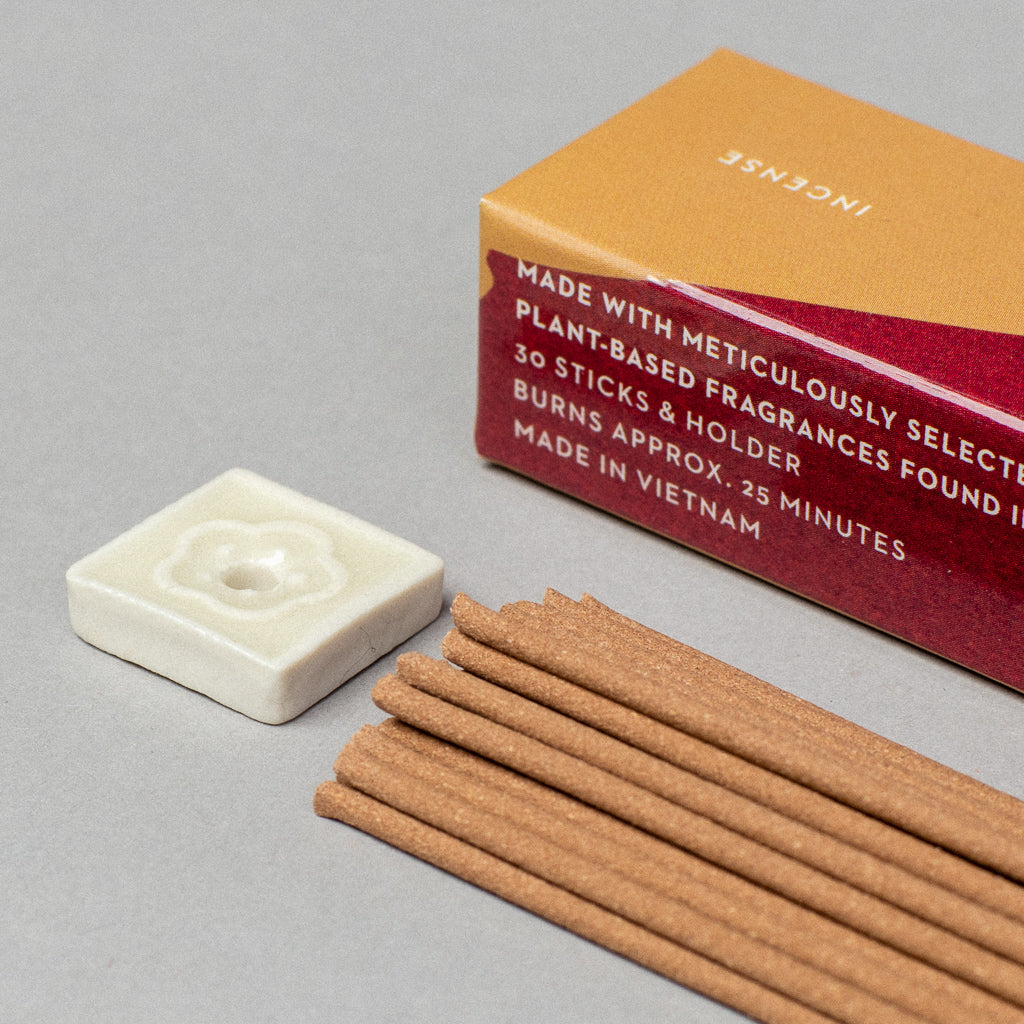 The Scentsual Japanese Incense box includes 30 incense sticks and a holder, boasting clean fragrances. Each stick burns for about 25 minutes. Made in Vietnam, the minimal packaging shows the box, sticks, and white holder on a gray surface.