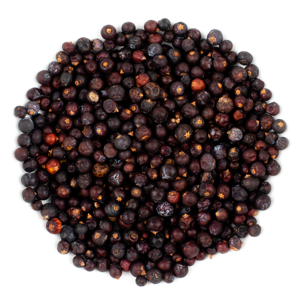 Organic Juniper Berries, known for their medicinal uses, are arranged in a circle against a white background. These small, round berries display varying shades of dark purple and brown, showcasing their distinctive texture.