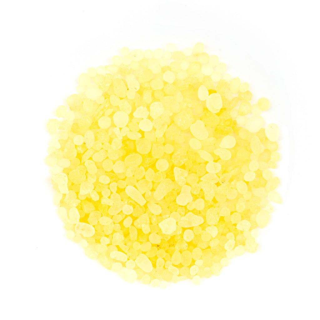 A circular pile of small, translucent yellow granules, resembling Mastic Gum Resin from Chios, Greece, sits on a white background. Varying slightly in size and shape, the granules provide a natural texture.