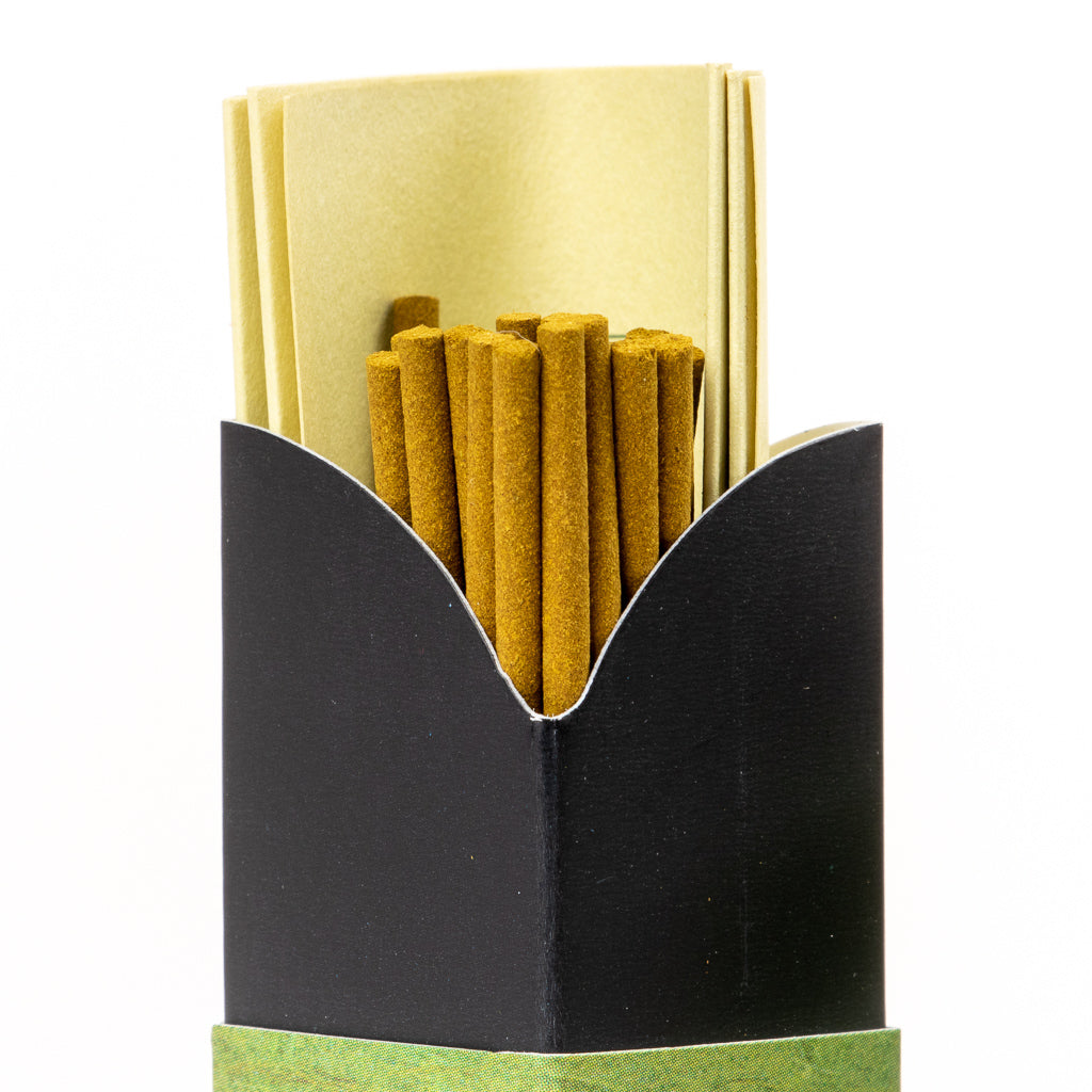 A partially opened black box reveals Mainichi Byakudan Premium Sandalwood Japanese Incense sticks and folded beige sheets inside. The green band complements the neatly arranged sticks, perfect for enhancing meditation sessions with their soothing aroma.